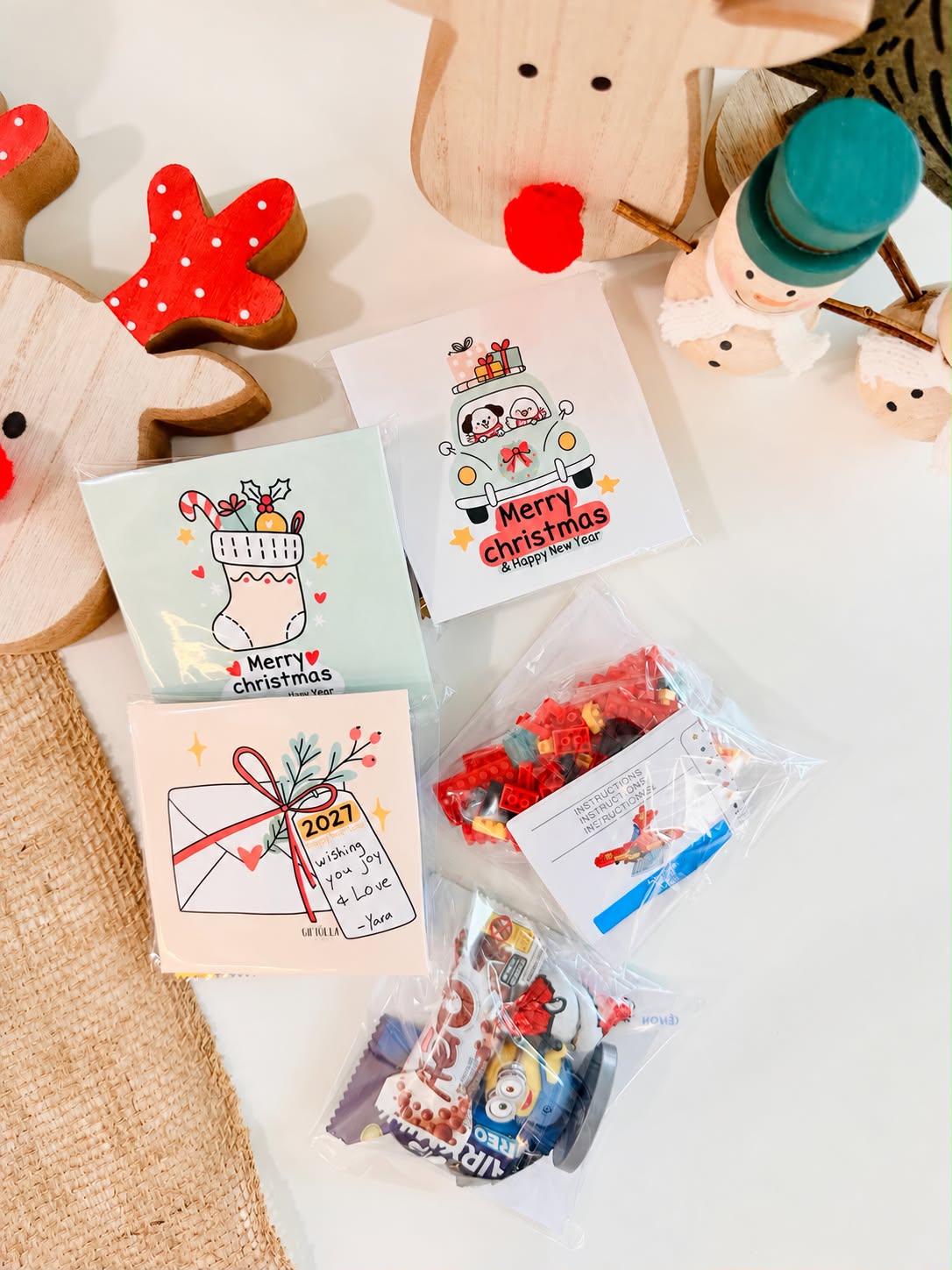 Christmas cards in clear bags filled with a mini brick toy set and chocolate snacks, ready to hand out