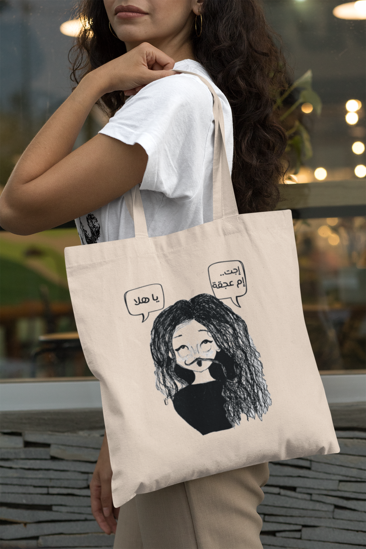 Mockup of a long-haired woman carrying the Um Ajqa tote bag